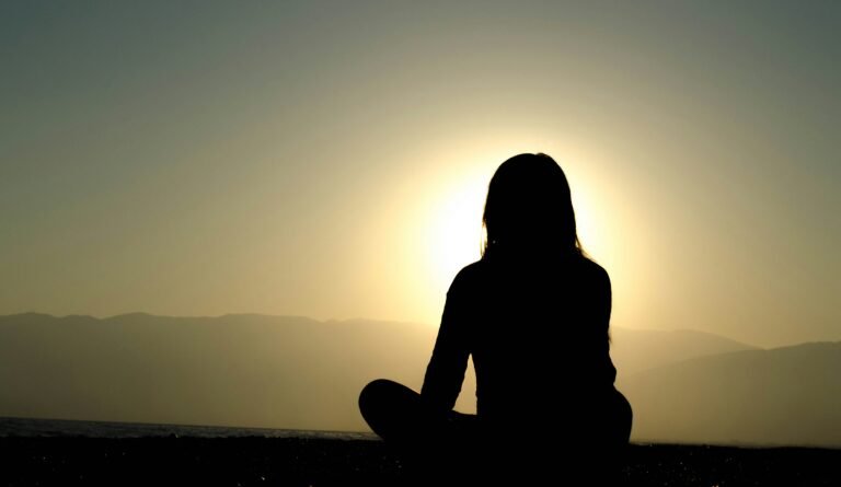A woman sitting with her legs crossed in front of the sun rise